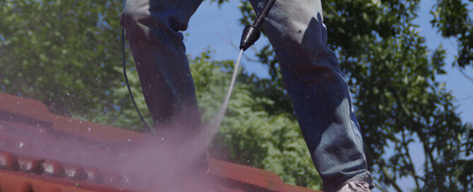Man pressure washing the roof