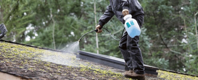 Worker treating a roof to prep for cleaning