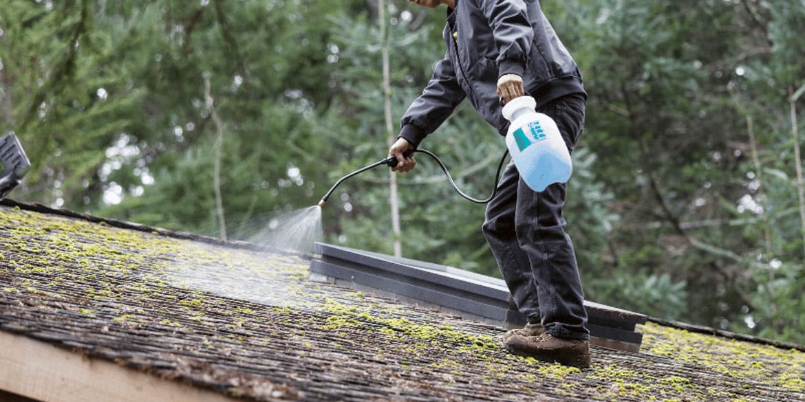 Worker treating a roof to prep for cleaning
