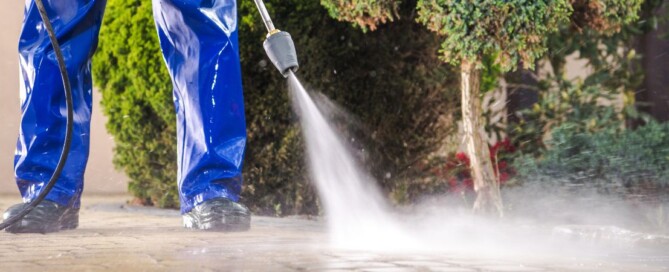 Worker powerwashing driveway